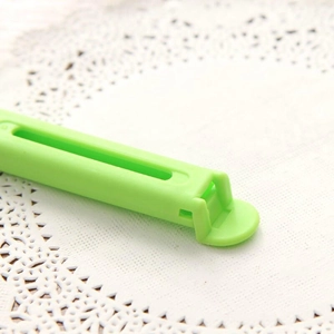 7cm green matte plastic food sealing clip for kitchen storage on a white lace background