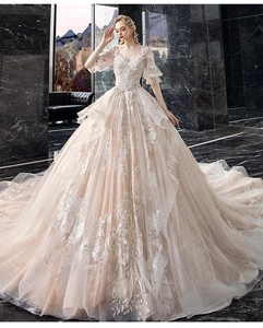 Detail of elegant bridal gown featuring deep V-neck, lace floral embroidery and long train