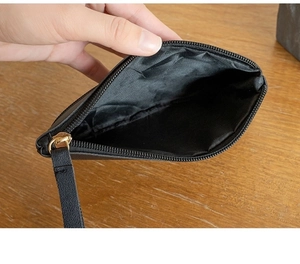 Detailed interior view of a black leather coin purse with golden zipper on wooden table