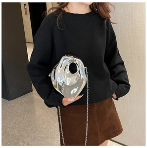 Chic silver acrylic clutch with metal chain shown on model in modern indoor setting