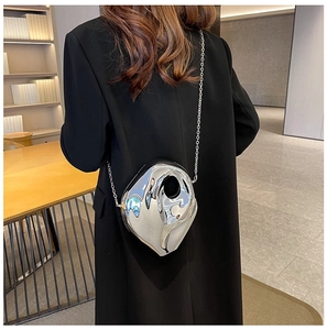 Close-up of a silver heart-shaped acrylic bag with a metallic chain on a black coat