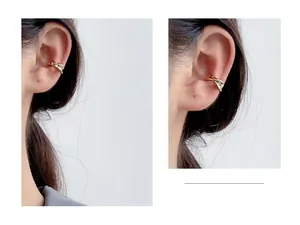 Close-up of golden twisted wave ear cuff in s925 silver worn on an ear without piercing