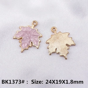 Macro view of alloy maple leaf pendant showing purple enamel and gold-plated texture