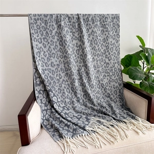 Detail of grey leopard jacquard scarf with soft fringe edges draped on a chair