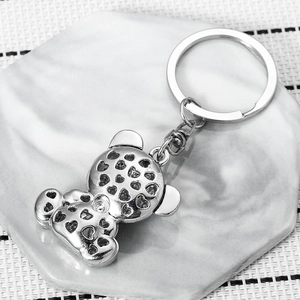 Silver bear keychain with heart cutout details on marble stone coaster for backpack