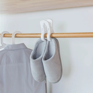 White heavy-duty plastic windproof pegs drying grey plush slippers on a wooden rod