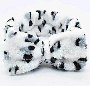 Close-up of soft coral fleece headband with black and white spotted leopard pattern