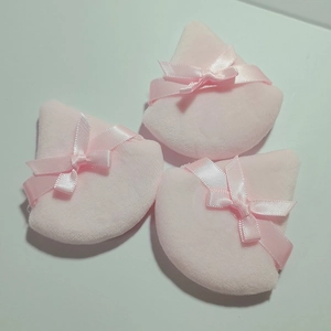 Three soft pink triangle powder puffs with cute ribbon bows on a white background