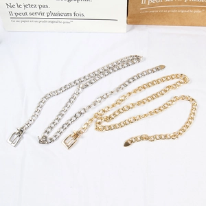 Detail view of stylish gold and silver metal chain belts on a white fabric background
