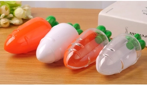Macro detail of carrot-shaped plastic containers for lip gloss on a wooden desk