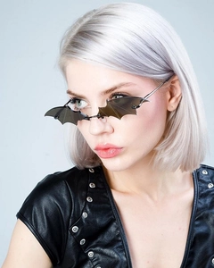 Close-up of model wearing black bat-shaped sunglasses with silver metal temples