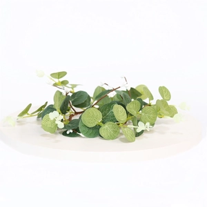 Detail of artificial eucalyptus wreath with green leaves and white berries on a white stand