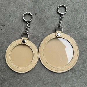 Detail showing two sizes of beige leather cat-shaped ita-bag badge holders with chains