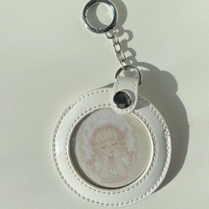 Detailed view of round white faux leather keychain holder with silver metal ring and chain
