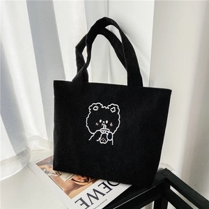 Detail of black corduroy tote bag with bear embroidery on a decorative magazine