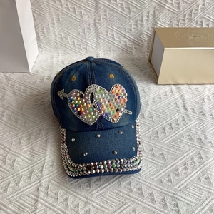 Detail of a dark blue denim baseball cap with sparkling rhinestone double heart and studs