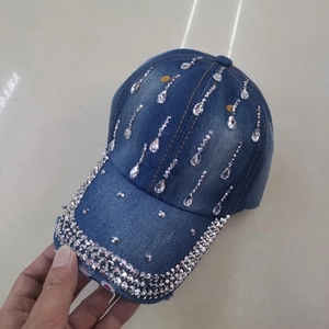 Close-up of blue denim baseball cap featuring large water-drop rhinestones and distressed edges