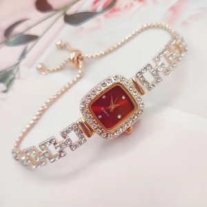 Macro shot of square gold rhinestone watch with deep red dial and adjustable chain strap