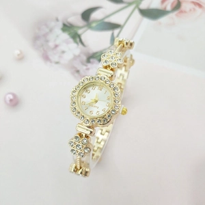 Macro shot of gold floral crystal watch with white dial and Arabic numerals