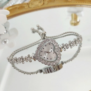Elegant heart-shaped rhinestone watch with silver floral bracelet on reflective surface