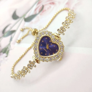 Close-up of golden heart-shaped watch with purple dial and rhinestone-encrusted floral bracelet