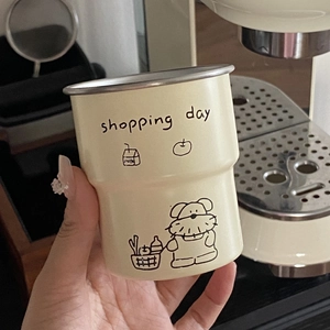 Camping mug with cartoon dog print and Shopping Day text held in hand by coffee machine