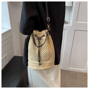Beige woven straw bucket bag with black drawstring and adjustable shoulder strap