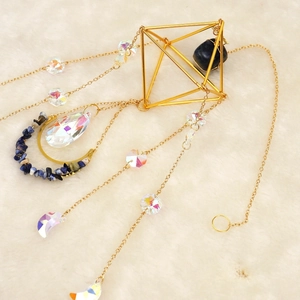 Golden suncatcher with blue raw stones and colorful crystal prisms on soft white fur