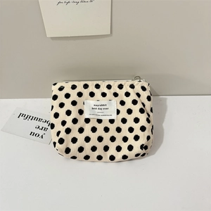 Macro detail of beige corduroy pouch with black polka dots and circular metal zipper pull