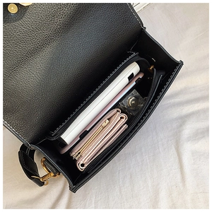 Top view of black crossbody bag interior showing power bank, phone, and wallet capacity