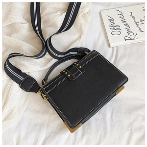Macro view of black pebbled PU leather crossbody bag with white contrast stitching and gold corners
