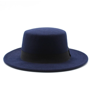 Detail of navy blue wool boater hat with a black grosgrain ribbon on white background