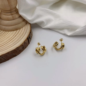 Macro shot of French style gold triple claw earrings on a natural wood background