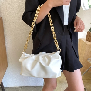 Detail of white pleated cloud bag with elegant gold chain strap and soft leather texture
