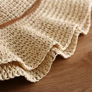 Close-up of natural beige straw hat featuring fine weave texture and a brown leather band