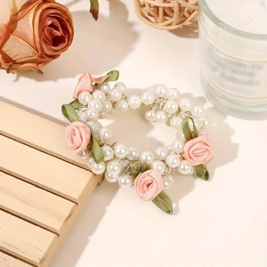 Detailed view of white pearls and pink fabric roses on an elastic hair tie band