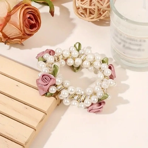 Detail of pearl scrunchie featuring pink fabric roses and delicate green leaf accents