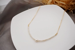 Detail of freshwater pearl necklace with gold chain and mini pearls on white tray