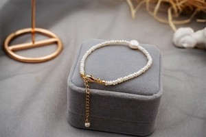 Detail of freshwater pearl bracelet with gold hardware on a gray velvet jewelry box