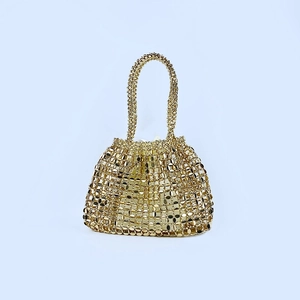 Detail view of a handmade woven golden metal mesh handbag with double handles and sequin finish