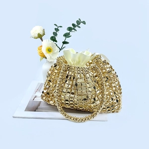 Detail of gold woven sequin handbag featuring cream drawstring inner pouch and metallic texture