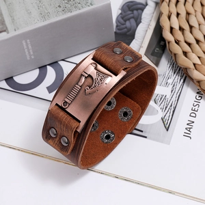 Detail of Viking battle axe metal plate on vintage brown leather wristband with rivets