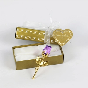 Detailed view of a purple crystal rose in an open gold heart box with white ribbon