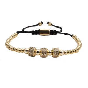 Détail d'un bracelet en cordon noir réglable avec perles dorées et breloques en zircone