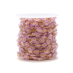 Detail of purple crystal flower chain with gold plated flat metal links on white spool