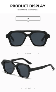 Detail view of glossy black square sunglasses with unique double bridge and grey lenses