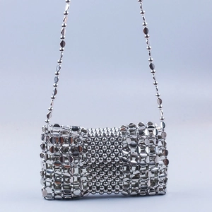 Close-up of silver woven chain links and metallic beaded texture on a crossbody bag