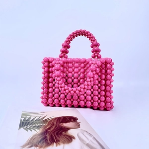 Detail of pink handmade acrylic pearl beads and woven handle of this elegant handbag