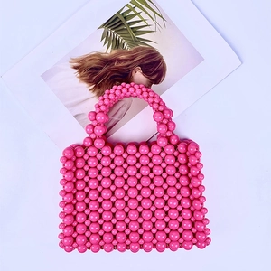 Flat lay of pink handmade acrylic beaded handbag with magazine on white background
