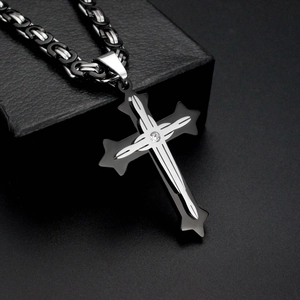 Macro shot of a black and silver diamond-set cross pendant on a matching metal chain